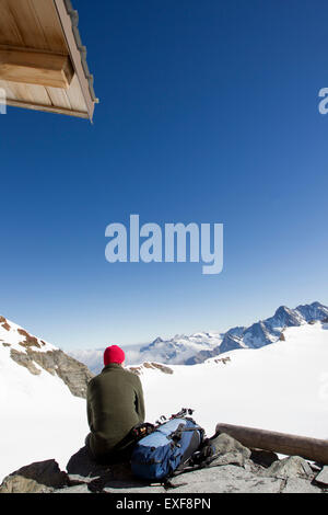 Vista posteriore dei maschi di escursionista guardando fuori al paesaggio dalla piattaforma di visualizzazione, Jungfrauchjoch, Grindelwald, Svizzera Foto Stock