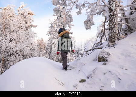 Ragazzo a piedi nella neve coperto di foreste di montagna, Nizhniy Tagil, nella Regione di Sverdlovsk, Russia Foto Stock