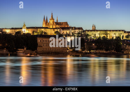 Illuminato il castello di Praga. Luce della Sera, il fiume Moldava in primo piano. Foto Stock