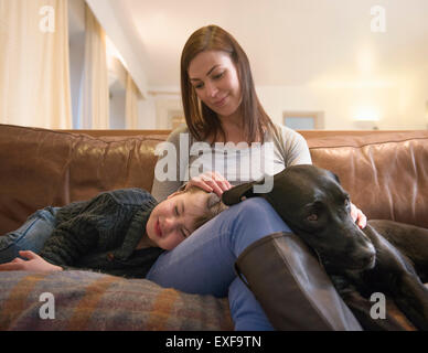 Madre e figlio stanco rilassante sul divano di casa con pet labrador Foto Stock