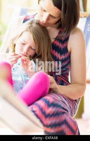 Figlia seduti sulla madre di giro Foto Stock