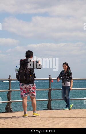 Uomo di prendere una fotografia della giovane donna su telefonato a Swanage Pier in giugno Foto Stock