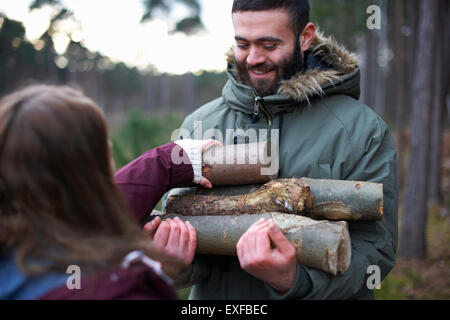 Giovani escursionismo giovane a raccogliere i log per il fuoco nella foresta Foto Stock