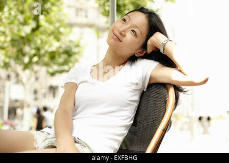 Giovane donna appoggiata sul gomito e guardando il sidewalk cafe, il Bund, Shanghai, Cina Foto Stock