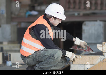 Operaio di fabbrica utilizzando cazzuola di finitura sul calcestruzzo calcestruzzo in fabbrica di rinforzo Foto Stock