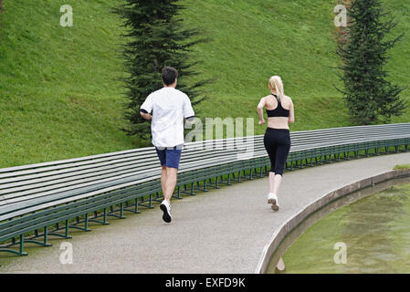 L uomo e la donna in esecuzione accanto al lago, vista posteriore Foto Stock