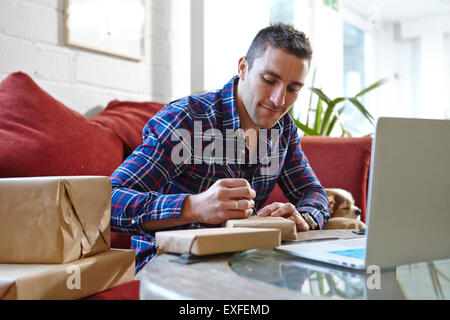 Metà uomo adulto indirizzo di scrittura sui pacchi in picture corniciai showroom Foto Stock