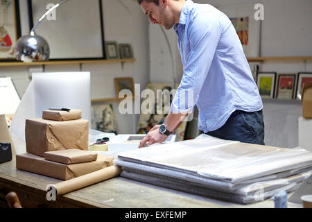 Uomo telai di incarto in Bubble Wrap su tavola in picture corniciai workshop Foto Stock