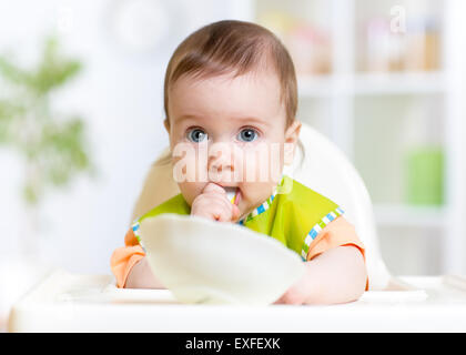 Allegro happy baby bambino seduto in poltrona con un cucchiaio Foto Stock