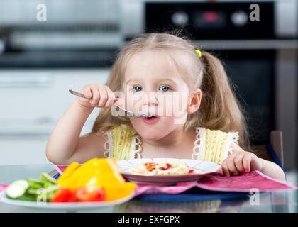 Kid mangiare spaghetti con verdure in vivaio o a casa Foto Stock