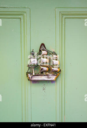 Porta in ottone respingente in forma di un galeone su una porta verde nel villaggio di Clovelly sulla North Devon Coast Foto Stock