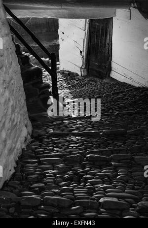 Strada basolata che passa attraverso una casa e giù al porto nel grazioso villaggio di Devon di Clovelly REGNO UNITO Foto Stock