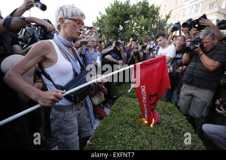 Atene, Grecia. 13 luglio 2015. Una donna che brucia una bandiera SYRIZA all'anti-austerità protesta al di fuori del parlamento greco. I Greci assemblati al di fuori del parlamento greco sotto la bandiera del "dobbiamo lasciare questo l'Europa". Essi hanno chiesto al governo di non dare alle richieste dei creditori greca per ulteriori misure di austerità, ma piuttosto di lasciare la zona euro. Credito: Michael Debets/Alamy Live News Foto Stock