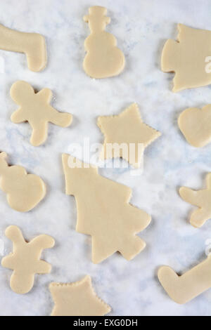 Elevato angolo di visione di un gruppo di impasto crudo cookie Natale forme su carta pergamena. Formato verticale. Foto Stock