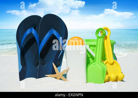 Blue Flip Flop, crema solare, giocattoli da spiaggia sulla spiaggia in estate Foto Stock