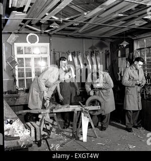 Anni Cinquanta foto storiche che mostra tre studenti o apprendisti in tuta in un workshop di essere insegnato a macchine per la lavorazione del legno o la falegnameria Foto Stock