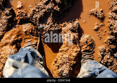 Un paio di scarpe da passeggio nel profondo della caviglia fango umido. Entrambe le scarpe sono coperti quasi alla sommità con fango appiccicoso dopo la recente pioggia rendendo difficile a piedi Foto Stock