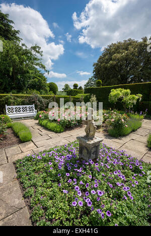 Il giardino di bandiera a Arley Hall nel Cheshire. Una statua e panca circondato da rose e biancheria da letto di estate. Foto Stock