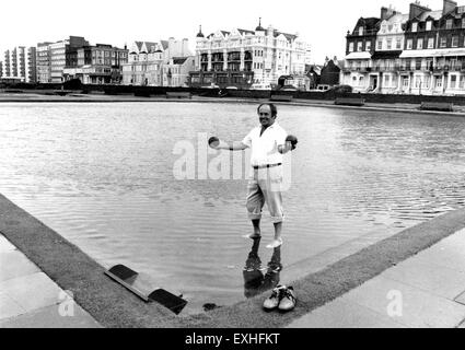 Uomo con boschi aloft sul inondati di bocce lungo il lungomare Hove 1987 Foto Stock