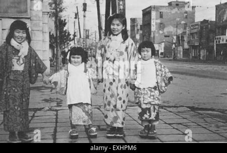 Questa fotografia cattura una scena di strada a Tokyo con bambini provenienti da una comunità mennonita, evidenziando la loro presenza culturale in Giappone. I bambini, indossando le tradizionali scarpe di legno, riflettono l'incrocio unico tra culture locali e mennonite. Foto Stock
