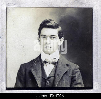 Questa fotografia dell'inizio del XX secolo cattura un giovane non identificato, probabilmente dalla fine degli anni '1800 all'inizio degli anni '1900 Il suo abbigliamento e la sua posa formale suggeriscono un ritratto destinato ad una collezione familiare o professionale, tipico delle convenzioni fotografiche del periodo. Foto Stock