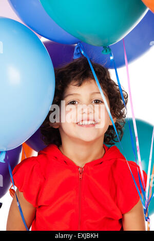 Adorabili piccolo bambino caucasico con capelli ricci indossando un colore rosso brillante top con cappuccio. La ragazza è in possesso di un mazzetto di colore luminoso h Foto Stock