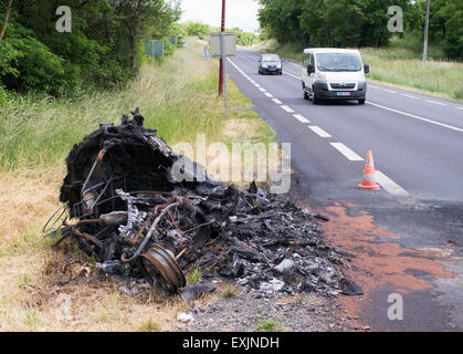 La bruciata rimane di un veicolo su strada a lato di una strada in Francia, Europa Foto Stock