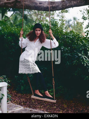 Piuttosto, giovane donna, divertendosi in piedi su una corda swing. Foto Stock