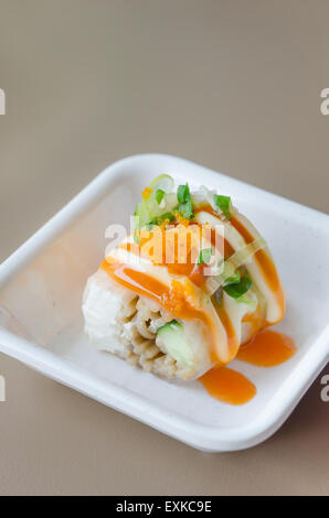 Rotolo di salmone sushi con gamberetti uovo sulla parte superiore nel piatto bianco Foto Stock