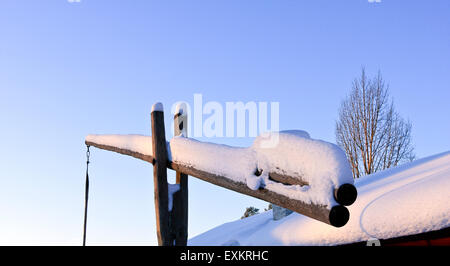 Leva, sfruttate dal passato in legno per prendere l'acqua. Ora coperte di appena sceso di neve. Cielo blu, tetto a destra. Foto Stock