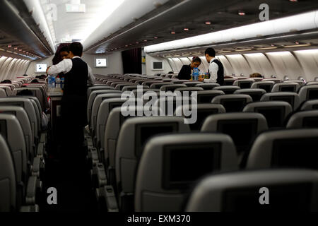 Equipaggio che serve rinfreschi ai passeggeri in un quasi deserte economia sulla cabina di qatar airlines da Giacarta a Doha Foto Stock