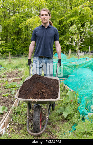 Ufficio lavoratori facendo alcuni volontari lavori di giardinaggio con carriole, Wedding, scavo, in guanti da giardinaggio Foto Stock