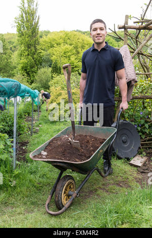 Ufficio lavoratori facendo alcuni volontari lavori di giardinaggio con carriole, Wedding, scavo, in guanti da giardinaggio Foto Stock