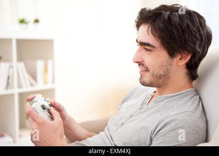Vista di un giovane uomo attraente per giocare con i videogiochi in un divano Foto Stock
