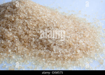 Lo zucchero di canna granuli disseminati su sfondo bianco Foto Stock