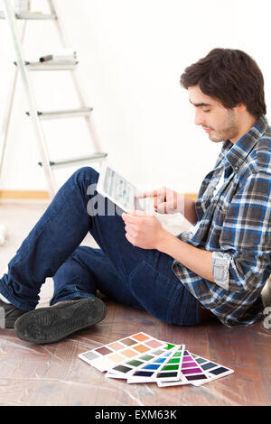 Vista di un giovane uomo che utilizza tablet mentre scegliendo il colore del suo appartamento Foto Stock