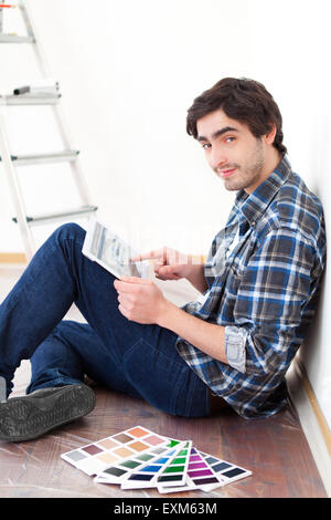 Vista di un giovane uomo che utilizza tablet mentre scegliendo il colore del suo appartamento Foto Stock