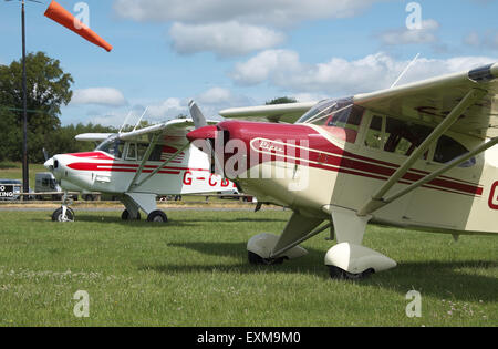 Vintage Piper PA-22 Tri-Pacer e Colt ( a ) posteriore aereo costruito negli anni cinquanta in un campo di aviazione di erba con manica a vento REGNO UNITO Foto Stock