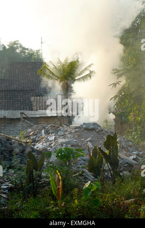 Fumo spesso da un falò inquinano l'aria sulla massa di rifiuti in un villaggio in java indonesia Foto Stock