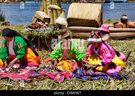 Tre donne indigene depongono le loro artigianato su coperte a vendere sull isola di Uros, il lago Titicaca, Perù, Sud America. Foto Stock