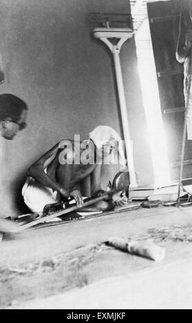 Bharat Anand vede Mahatma Gandhi che gira sullo strumento a rotazione dhanush takli nella sua capanna a Sevagram Ashram wardha nagpur india 1940 foto vintage anni '1900 Foto Stock