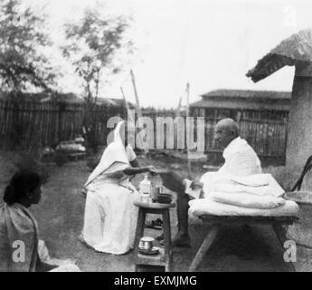 Kasturba Gandhi e il Mahatma Gandhi avente la prima colazione nella parte anteriore del Mahatma Gandhi capanna a Sevagram Ashram ; 1940 n. MR Foto Stock