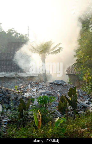 Fumo spesso da un falò inquinano l'aria sulla massa di rifiuti in un villaggio in java indonesia Foto Stock