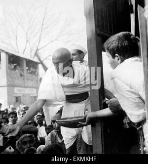 Il Mahatma Gandhi a raccogliere donazioni per Harijan fondo con una cesta in mano a una stazione ferroviaria a modo di Assam Foto Stock