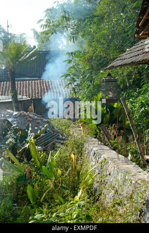 Fumo spesso da un falò inquinano l'aria sulla massa di rifiuti in un villaggio in java indonesia Foto Stock