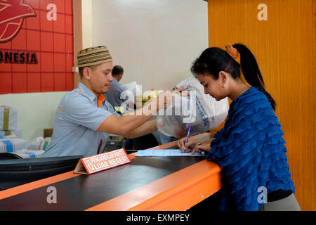 Femmina firma del cliente per una consegna presso il principale ufficio postale a malang java indonesia Foto Stock