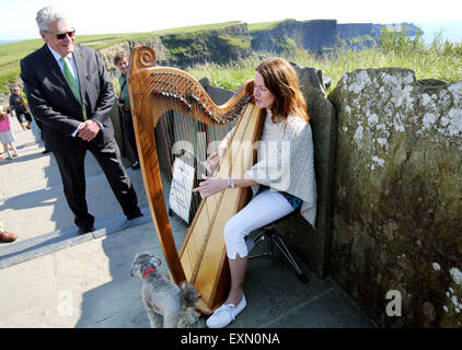 Ballyvaugha, Irlanda. Il 15 luglio 2015.Il Presidente tedesco Joachim Gauck visiti le scogliere di Moher e ascolta la musica di un musicista di strada nella contea di Clare, Irlanda, 15 luglio 2015. Gauck è su una tre giorni di visita in Irlanda. Credito: dpa picture alliance/Alamy Live News Foto Stock