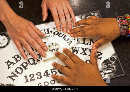 In prossimità di due teenager le mani giocando con una Ouija Board. Foto Stock