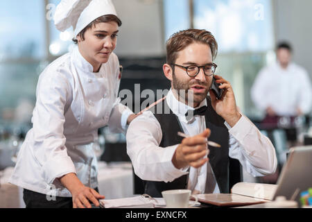 Ristorante lo chef e il manager discute prenotazioni Foto Stock