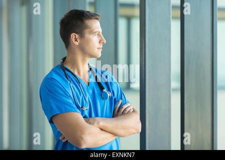 Riflessivo medico guardando attraverso la finestra di ufficio Foto Stock